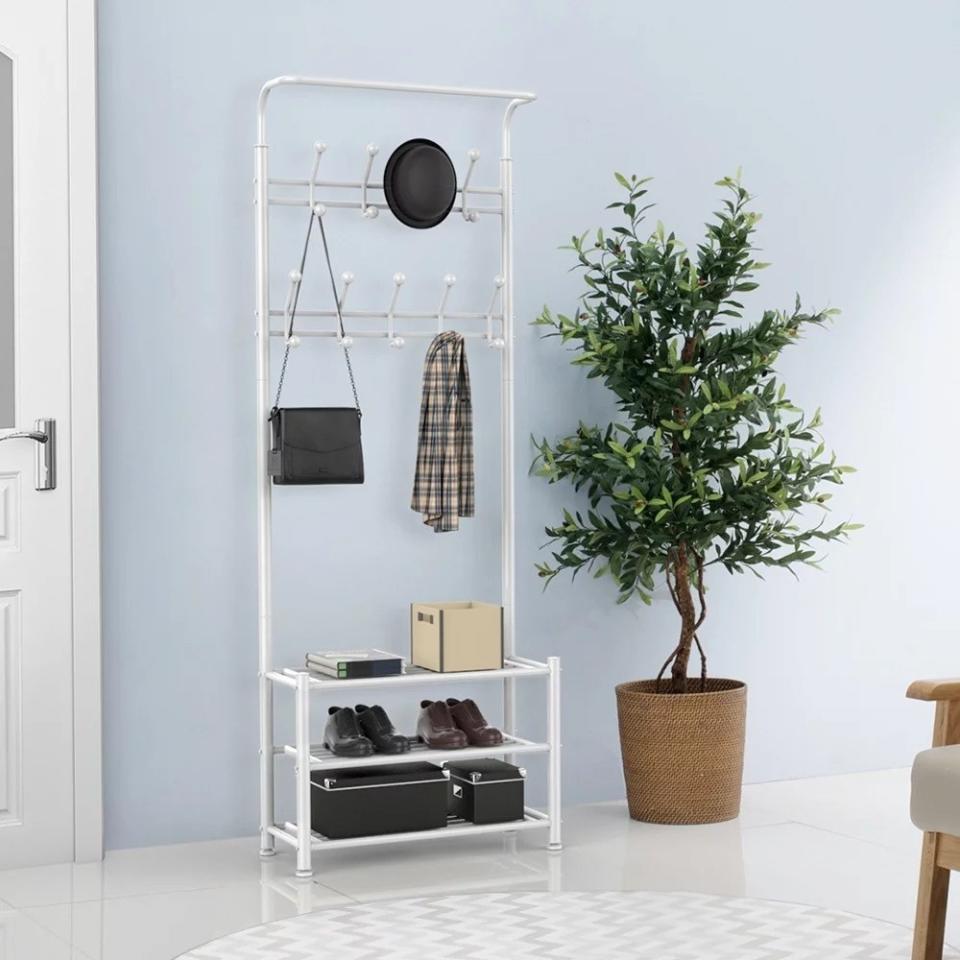 the white hall tree next to a door holding several items