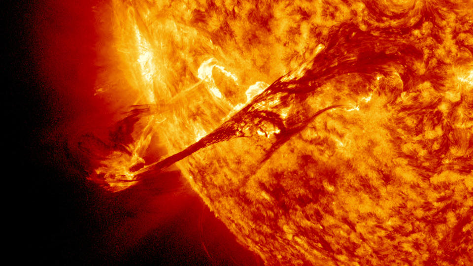 a bright, fiery yellow-organ-colored sun shines from the right and fills two-thirds of the frame.  the star spews an arc of plasma high above its surface.  so hot