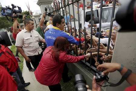 Venezuela's President Nicolas Maduro salutes the people through a fence before his vote in a polling center in Caracas, June 28, 2015. REUTERS/Jorge Dan Lopez