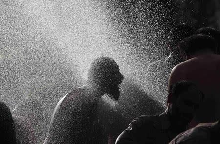 An anti-government protester takes a morning bath with others at a public pump during the Revolution March in Islamabad September 3, 2014. REUTERS/Akhtar Soomro