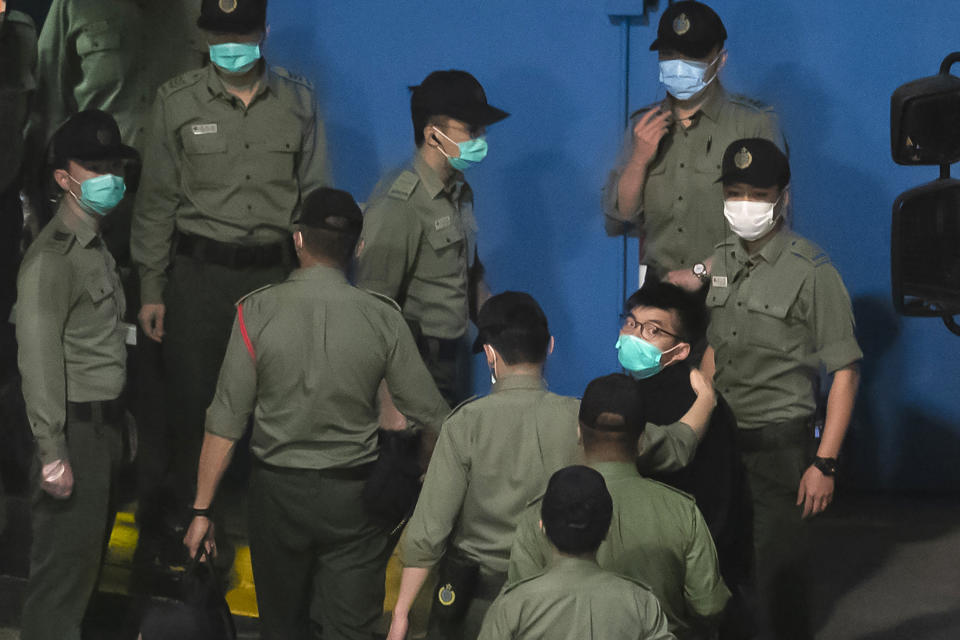 Joshua Wong, right, one of the 47 pro-democracy Hong Kong activists, is escorted by Correctional Services officers to prison in Hong Kong, early Tuesday, March 2, 2021. Hong Kong police on Monday brought 47 pro-democracy activists to court on charges of conspiracy to commit subversion under the national security law imposed on the city by Beijing last year. (AP Photo/Kin Cheung)