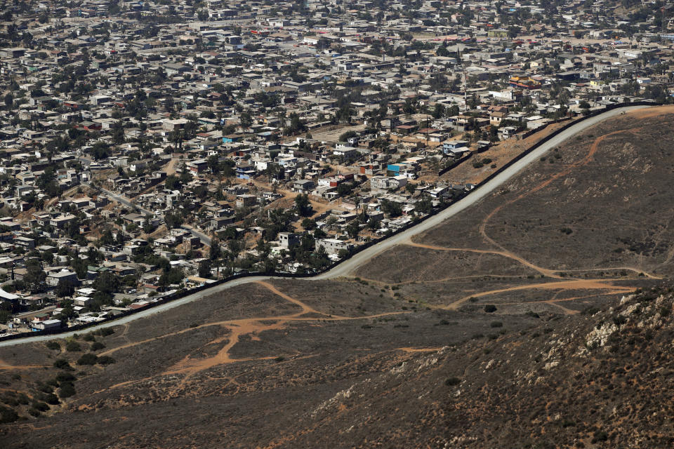 FILE - In this Thursday, June 28, 2018 file photo a road runs alongside a border wall that separates Tijuana, Mexico, top, from San Diego. The Tijuana and San Diego border crossing is the world's busiest land border crossing, but also now sees relatively few illegal crossings.(AP Photo/Jae C. Hong,File)