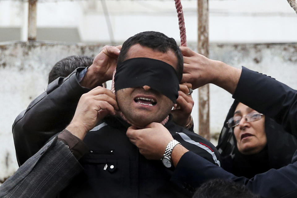 This picture provided by ISNA, a semi-official news agency, taken on Tuesday, April 15, 2014 shows Samereh Alinejad, right, and her husband Abdolghani, left, removing the noose from the neck of blindfolded Bilal who was convicted of murdering their son Abdollah in the northern city of Nour, Iran. Bilal who was convicted of killing Abdollah Hosseinzadeh, was pardoned by the victim's family moments before being executed. (AP Photo/ISNA, Arash Khamoushi)
