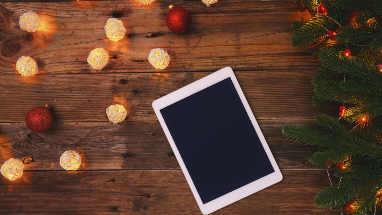 electronic tablet on wooden background with christmas ornaments