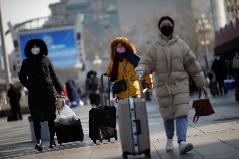 People wearing face masks walks outside Beijing Railway Station as the country is hit by an outbreak of the new coronavirus, in Beijing