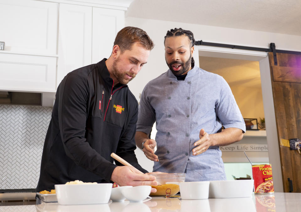 In a photo provided by Hormel Foods, Minnesota Vikings wide receiver Adam Thielen, left, and chef Kenneth Temple prepare a Minnesota-inspired chili dip Jan. 15, 2019, in Austin, Minn. “The beautiful thing about it is chili and football go hand in hand,” Temple says, noting Hormel was a partner with the NFL as far back at the 1950s. “At tailgates or with friends at a viewing party or wherever, it is easy to accommodate a larger crowd.” (Hormel Foods via AP)