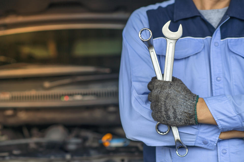 Professional Mechanic in the garage. Auto repair garage. Hands of car mechanic with wrench in garage.