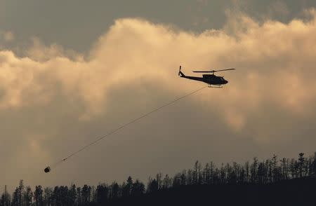 A helicopter flies over a wildfire south west of the town of Cache Creek, British Columbia, Canada July 18, 2017. REUTERS/Ben Nelms