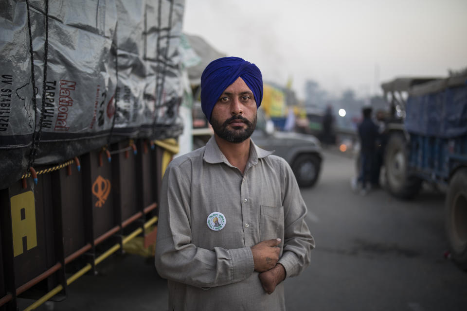 Farmer Harinder Singh, 28, stands for a photograph next to his tractor parked on a highway during a protest against new farm laws, at the Delhi-Haryana state border, India, Wednesday, Dec. 2, 2020. The protests started in September but drew nationwide attention last week when the farmers marched from northern Punjab and Haryana, two of India's largest agricultural states. Every day, thousands more join the protesters. (AP Photo/Altaf Qadri)