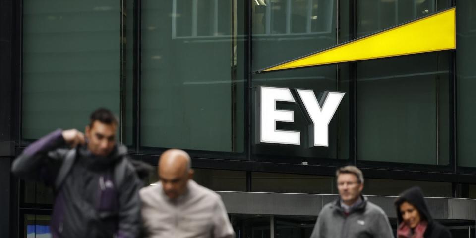 Pedestrians walk in front of the entrance to EY's head office in London.