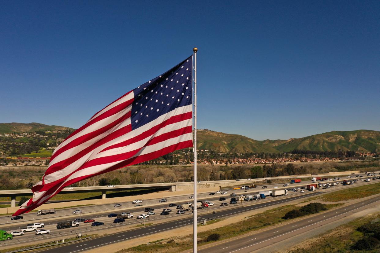 An aerial image taken on February 8, 2023 shows cars and trucks driving past a US flag in traffic on the 91 Freeway in Anaheim Hills, California. - A proposed infrastructure project called the 241-91 Express Connector Project would connect vehicles from 91 Express Lanes to the toll road. (Photo by Patrick T. Fallon / AFP) (Photo by PATRICK T. FALLON/AFP via Getty Images)