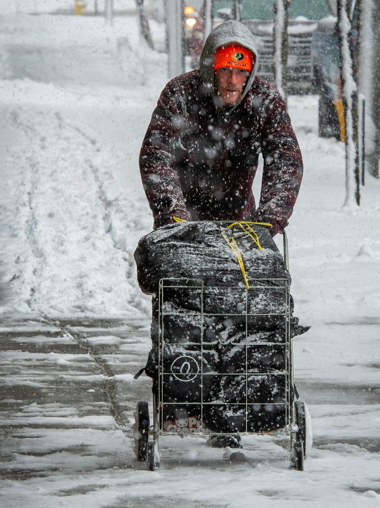 Michael Richard pushes a folding grocery cart with his belongings on a snow-covered sidewalk in Main South, Worcester, Tuesday.