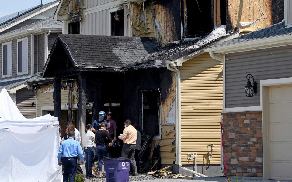 Investigators stand outside the burned Diol family home