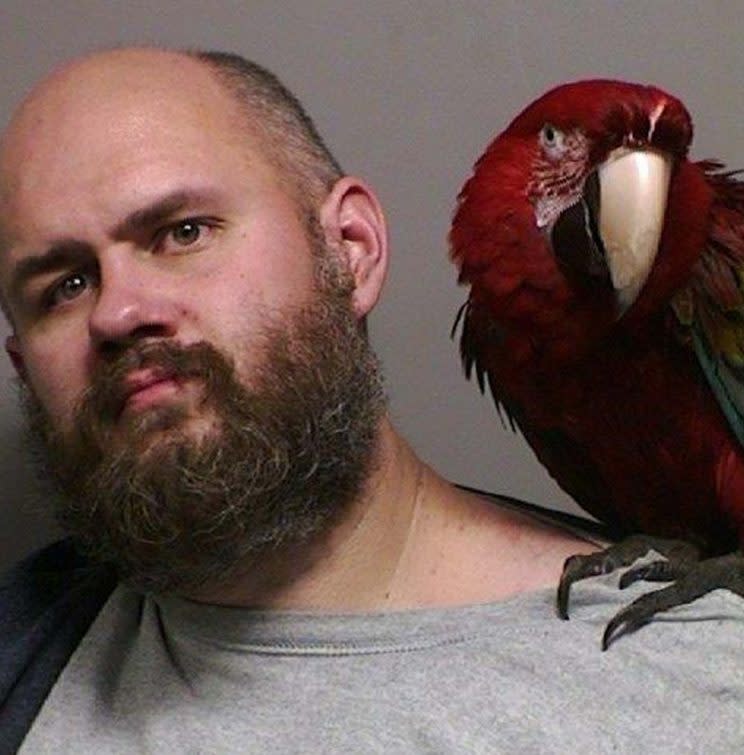 A man has posed with his pet macaw in an unusual mugshot