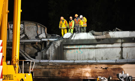 Workers examine a damaged bridge section at the site of the derailment of Amtrak train 501 in Dupont, Washington, U.S., December 19, 2017. REUTERS/Thomas James