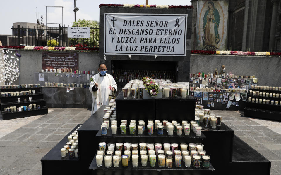 A priest blesses a memorial for COVID-19 victims installed outside the Basilica of Guadalupe in Mexico City, Wednesday, April 14, 2021. (AP Photo/Eduardo Verdugo)