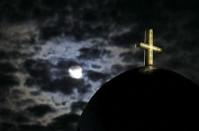 The moon rises above a church on the Greek island of Santorini, Greece, July 1, 2015. REUTERS/Cathal McNaughton