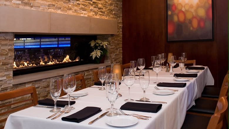 fireplace and long banquet table with linens and stemware