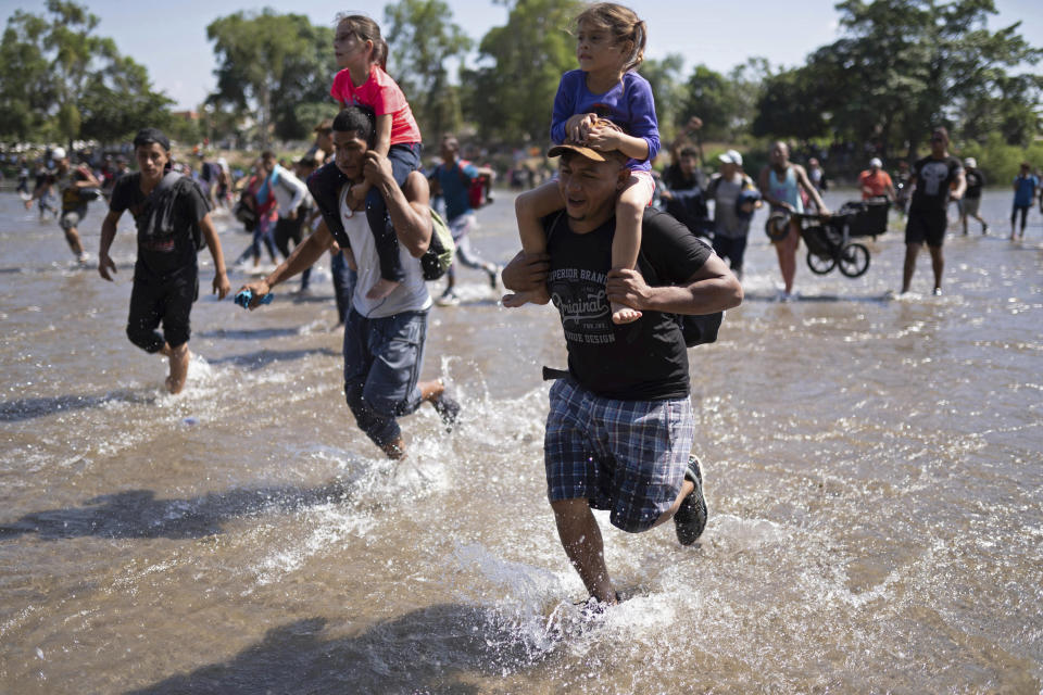 Central American migrants carry children across the Suchiate River from Guatemala to Mexico, near Ciudad Hidalgo, Mexico, Monday, Jan. 20, 2020, in hopes of convincing Mexican authorities to allow them passage through the country so they could reach the United States. (AP Photo/Santiago Billy)