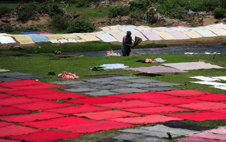 <p>An Indian laundry worker washes clothes next to the polluted Adyar river in Chennai on April 1, 2016. </p>