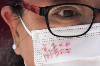 A woman wearing a face mask written with the words "Gaokao" as students take part on the first day of China's national college entrance examinations, known as the gaokao, in Beijing, Tuesday, July 7, 2020. China's college entrance exams began in Beijing on Tuesday after being delayed by a month due to the coronavirus outbreak. (AP Photo/Andy Wong)