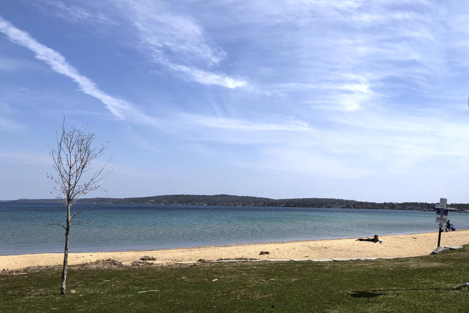 In this May 2, 2019 photo, clinch Park Beach in Traverse City, Mich., is mostly deserted. The beach on Lake Michigan's Grand Traverse Bay is one of the most popular warm-weather spots in this tourist town a four-hour drive northwest of Detroit. With summer vacation season looming, the city normally would be expecting a crush of visitors. But shops are closed and festivals have been canceled, and it's uncertain how many will come. Some local residents have mixed feelings about crowds descending on the area, which might cause the number of virus cases to rise. (AP Photo/John Flesher)