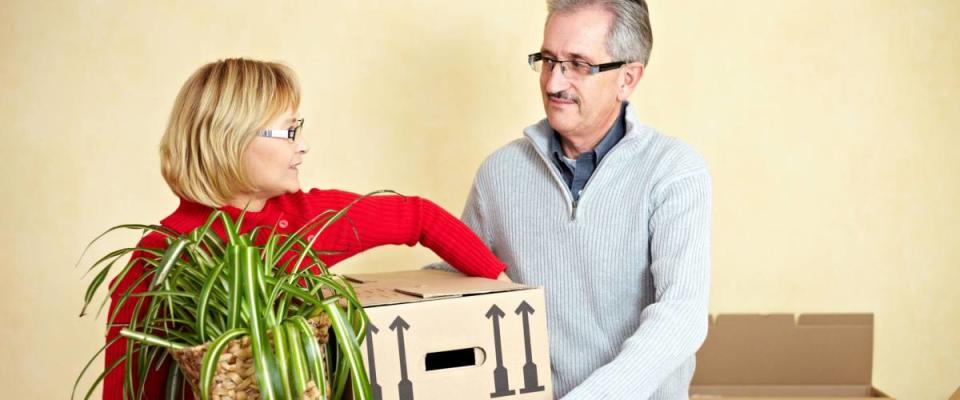 Two happy senior people with many moving boxes