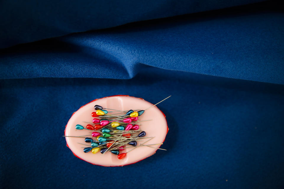 In this picture taken Tuesday, May 21, 2019, needles sit on a piece of fabric at a tailor shop that produces traditional clothing in Luncavita, Romania. Valentina Radu worked in Italy, but when her husband lost his job there, they struggled to pay the rent and decided to come home where they used European Union funds to buy a small farm and she opened a tailor's shop. (AP Photo/Vadim Ghirda)