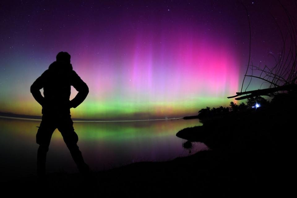 silhouette of a person standing in front of the northern lights