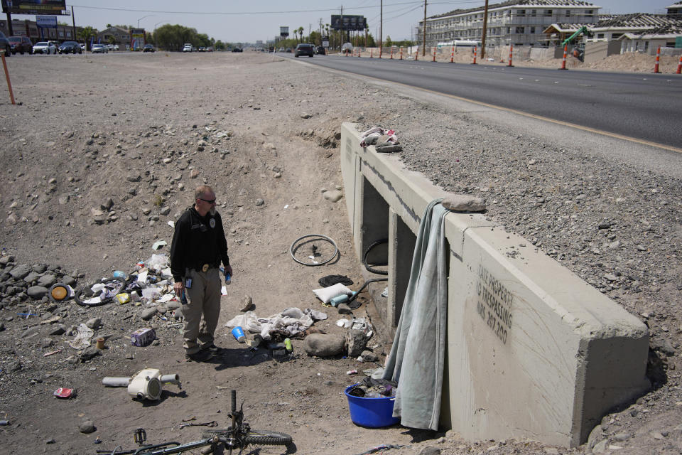 Mark Paulson, a Public Response and Code Enforcement officer, holds cans of cold water while checking on a homeless encampment, Wednesday, July 10, 2024, in Henderson, Nev. About 14 officers from the Office of Public Response drove around the city Wednesday offering water, electrolytes, free bus tickets and rides to cooling centers during a heat emergency. (AP Photo/John Locher)