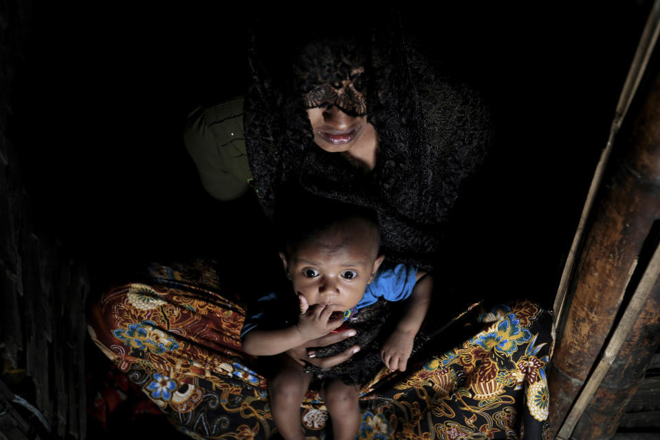 FILE - In this Dec. 2, 2016 file photo, Mohsena Begum, a Rohingya who escaped to Bangladesh from Myanmar, holds her child at the entrance of a room of an unregistered refugee camp in Teknaf, near Cox's Bazar, a southern coastal district about, 296 kilometers (183 miles) south of Dhaka, Bangladesh. "They drove us out of our houses, men and women in separate lines, ordering us to keep our hands folded on the back of our heads," says 20-year-old Mohsena Begum, her voice choking as she described what happened to the little village of Caira Fara, which had long been home to hundreds of members of Myanmar's minority Rohingya community. (AP Photo/A.M. Ahad)