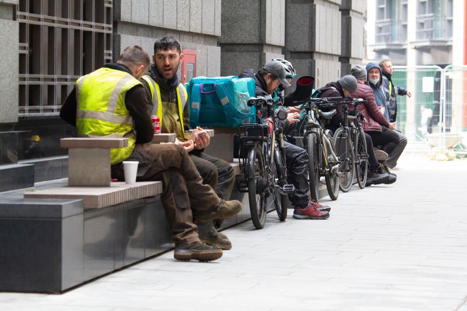 Deliveroo delivery riders amongst workers on their lunchbreak, looking at their phones awaiting for jobs, City of London, during Coronavirus Covid-19 Pandemic lockdown