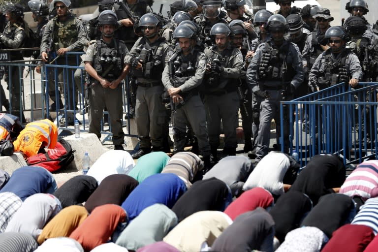 Israeli border guards keep watch as Palestinian worshippers pray outside Jerusalem's Old City overlooking the Al-Aqsa mosque compound on July 28, 2017