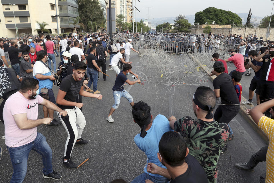 Protesters try to remove barbed wire during a protest against French President Macron's comments over Prophet Muhammad caricatures, near the Pine Palace, which is the residence of the French ambassador, in Beirut, Lebanon, Friday, Oct. 30, 2020. (AP Photo/Bilal Hussein)