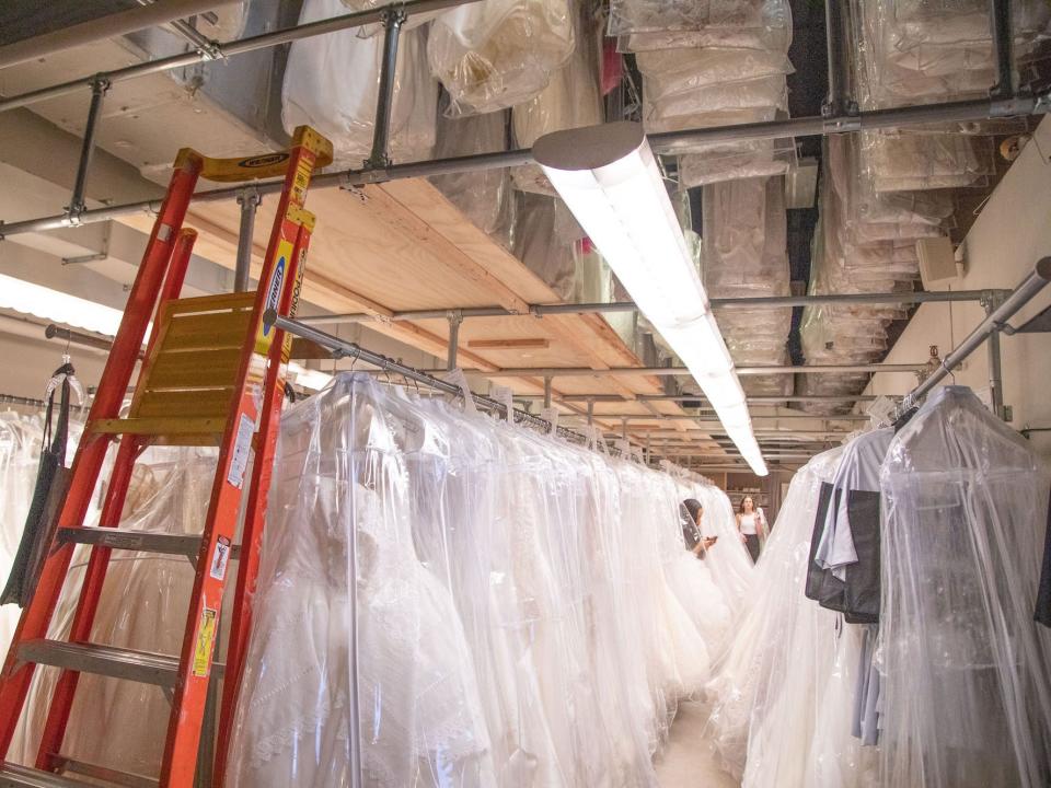 A large room with wedding dresses on racks.