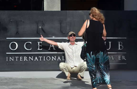 A tourist poses for pictures after the Trump logo was removed from the entrance to the Trump Ocean Club International Hotel and Tower luxury complex in Panama City.