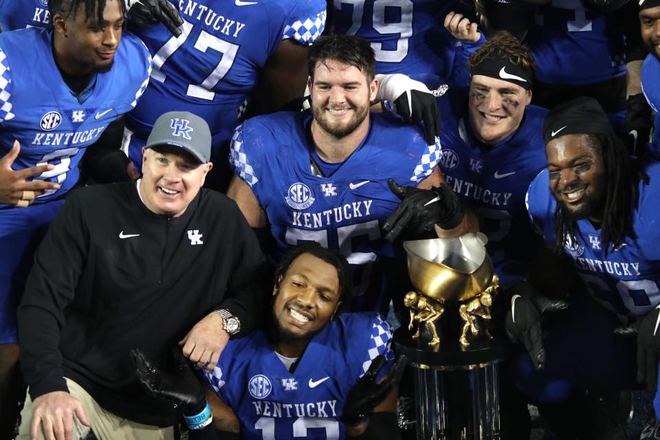 Kentucky’s coach Mark Stoops posses with the team and the Governor’s Cup trophy for winning the game against Louisville.Nov. 26, 2022