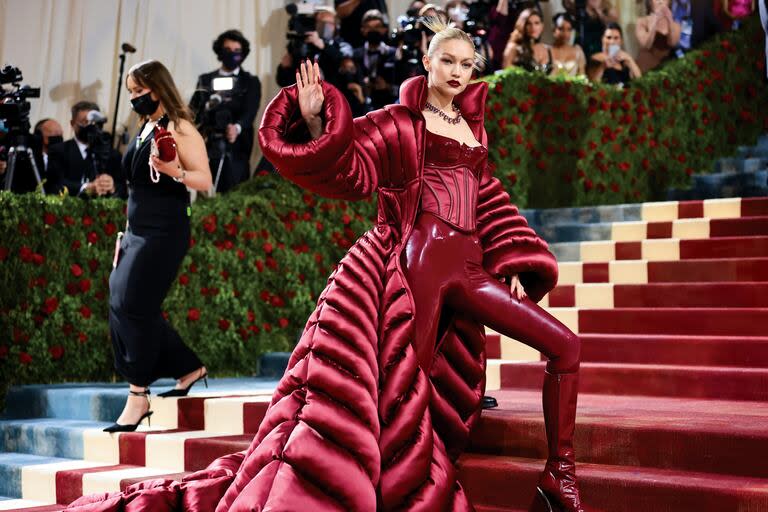 Inspirada en el glamour de la Edad Dorada de Estados Unidos, específicamente de la ciudad de Nueva York, Gigi Hadid llegó a la Met Gala 2022 con unos leggins de vinilo, un corset, unas botas altas de taco fino y un increíble tapado acolchado y satinado. Todo en un llamativo color burdeos 