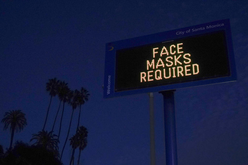 FILE - In this Dec. 8, 2020, file photo, a sign reminding people to wear a mask stands along the Pacific Coast Highway in Santa Monica, Calif. After a punishing fall that left hospital struggling, some Midwestern states are seeing a decline in new coronavirus cases. But the signs of improvement are offset by the infection’s accelerating spread on both coasts. (AP Photo/Jae C. Hong, File)