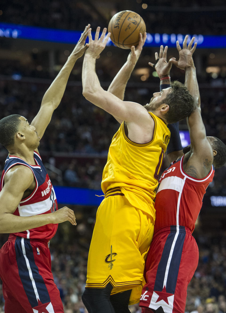 Cleveland Cavaliers' Kevin Love (0) is fouled by Washington Wizards' Otto Porter Jr., left, as teammate John Wall, right, also defends during the first half of an NBA basketball game in Cleveland, Saturday, March 25, 2017. (AP Photo/Phil Long)