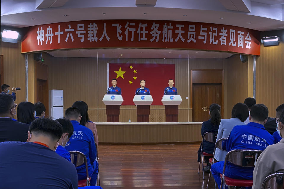 Chinese astronauts for the upcoming Shenzhou-16 mission from left, Gui Haichao, Jing Haipeng and Zhu Yangzhu are seen behind glass during a meeting of the press at the Jiuquan Satellite Launch Center in northwest China on Monday, May 29, 2023. China's space program plans to land astronauts on the moon before 2030, a top official with the country's space program said Monday. (AP Photo/Mark Schiefelbein)