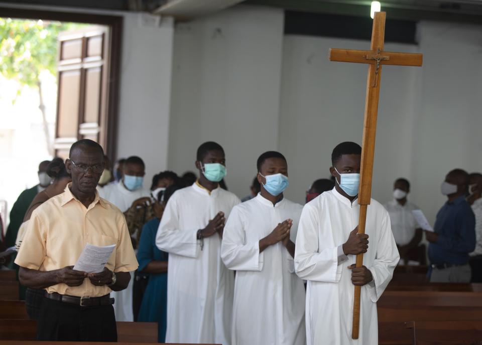 Altar boys carry a cross while wearing face masks to curb the spread of the new coronavirus, during Sunday Mass at St-Louis church, in Port-au-Prince, Sunday, July 11, 2021, four days after President Jovenel Moise was assassinated in his home. (AP Photo/Joseph Odelyn)