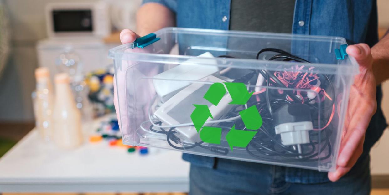 man holding recycling container filled with electronics