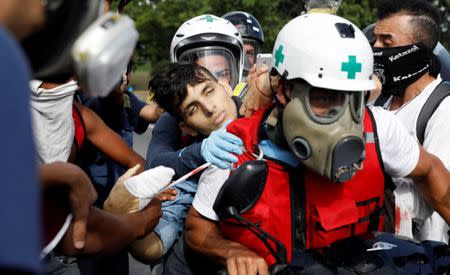 An injured opposition supporter is helped by volunteer members of a primary care response team outside an air force base during clashes with riot police forces at a rally against Venezuelan President Nicolas Maduro's government in Caracas, Venezuela June 22, 2017. REUTERS/Carlos Garcia Rawlins