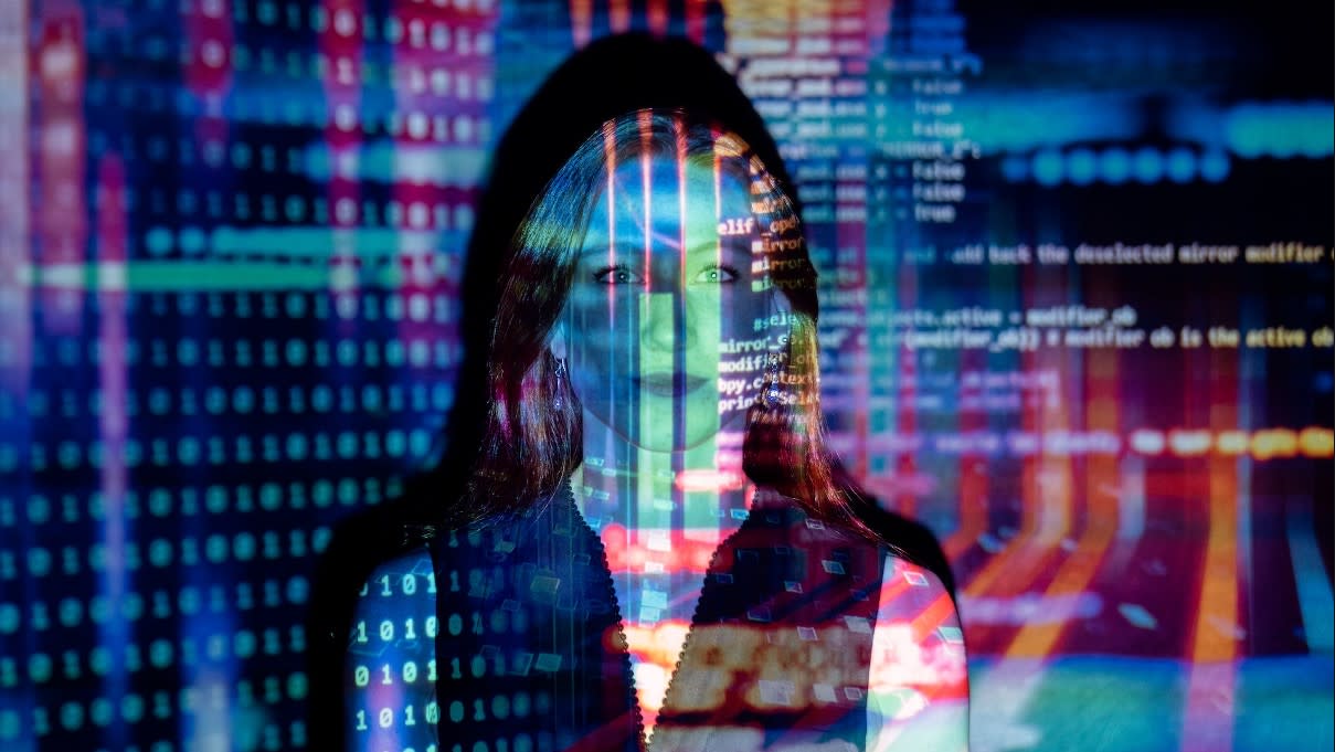  The future of AI art - Woman overlaid by projection of computer code in vibrant colours 