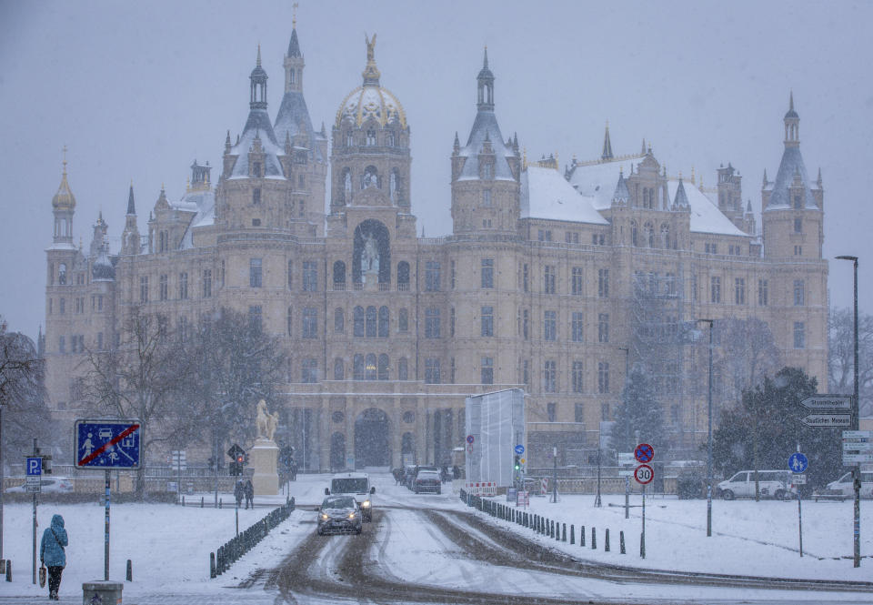 Roads in front of Schwerin Castle are covered in snow, in Schwerin, Germany, Tuesday Dec. 5, 2023. Heavy snowfall in places and temperatures below freezing are hampering traffic in northern Germany. (Jens Büttner/dpa via AP)