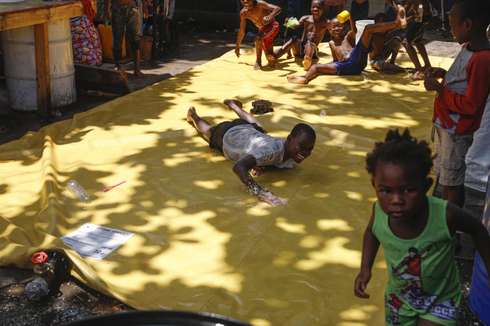 Children play on a slip-and-slide at a shelter for families displaced by gang violence, in Port-au-Prince, Haiti, Friday, March 22, 2024. (AP Photo/Odelyn Joseph)