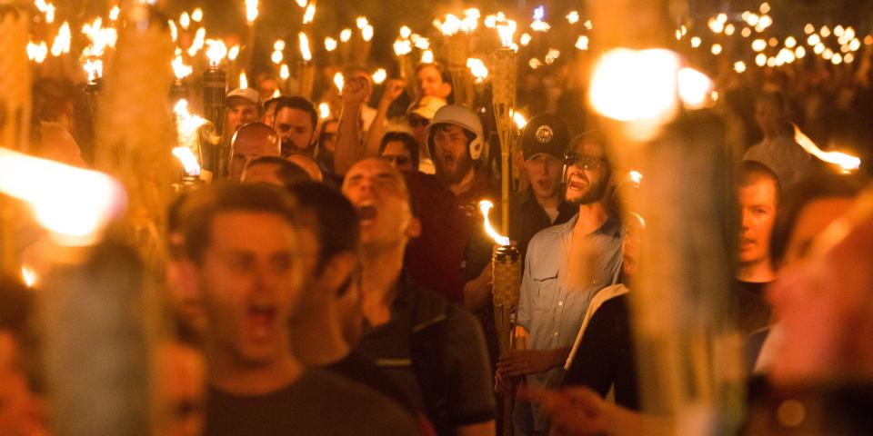 Several demonstrators holds tiki torches lit by fire.