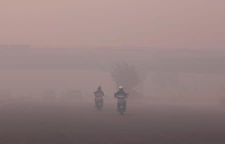 FILE PHOTO: Commuters make their way through heavy smog in New Delhi, India, October 31, 2016. REUTERS/Adnan Abidi/File photo