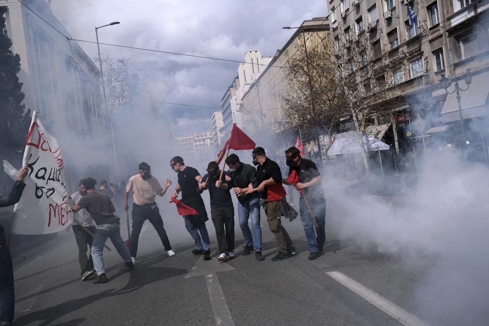 Demonstrators try to avoid tear gas thrown by riot police during clashes in Athens, Greece, Sunday, March 5, 2023. Thousands protesters, take part in rallies around the country for fifth day, protesting the conditions that led the deaths of dozens of people late Tuesday, in Greece's worst recorded rail accident. (AP Photo/Aggelos Barai)